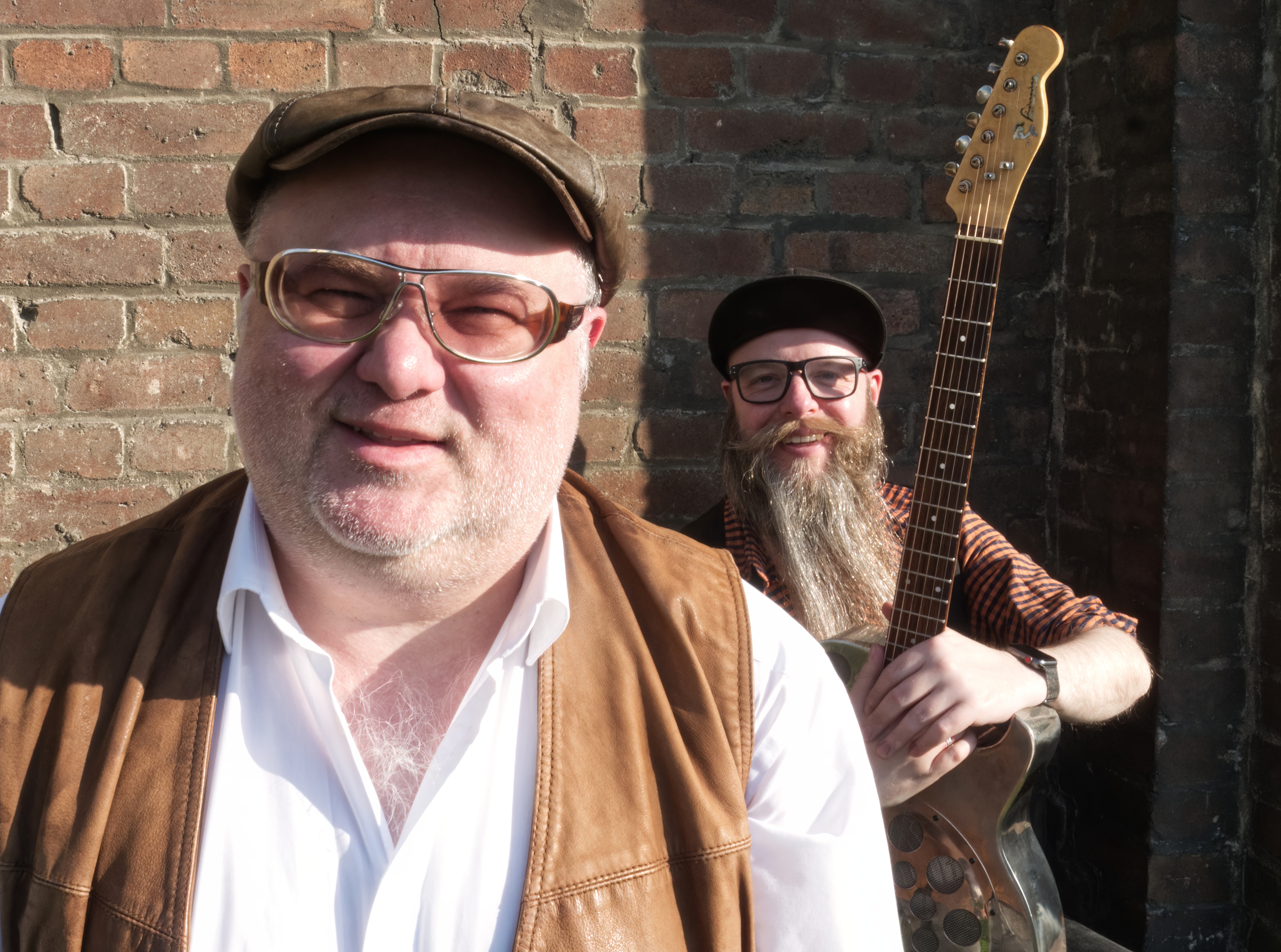 Chris Kramer Duo Chris Kramer Duo mit Gitarre vor einer Backsteinhaus